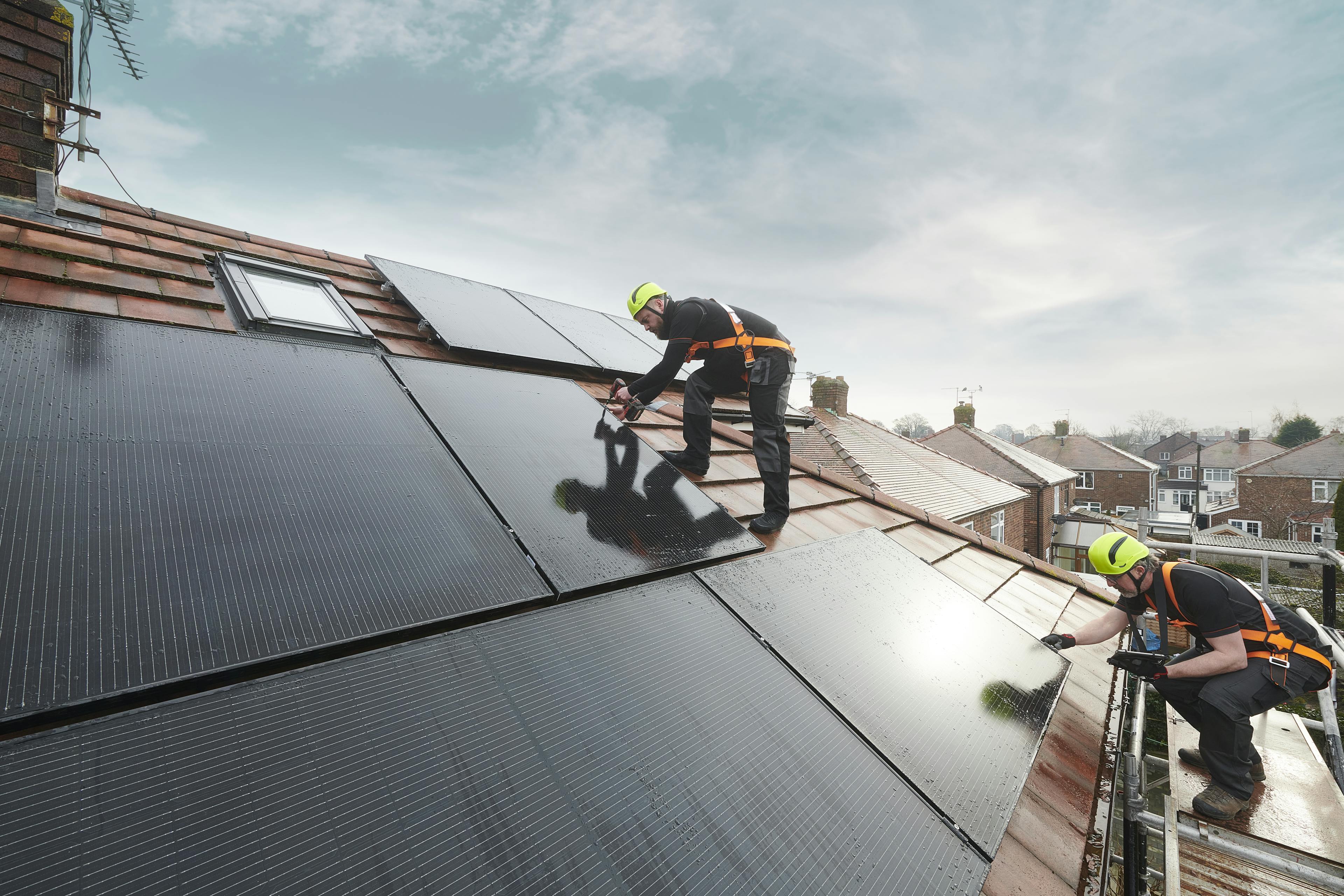 Zwei Handwerker montieren Solarpanels auf einem Dach.