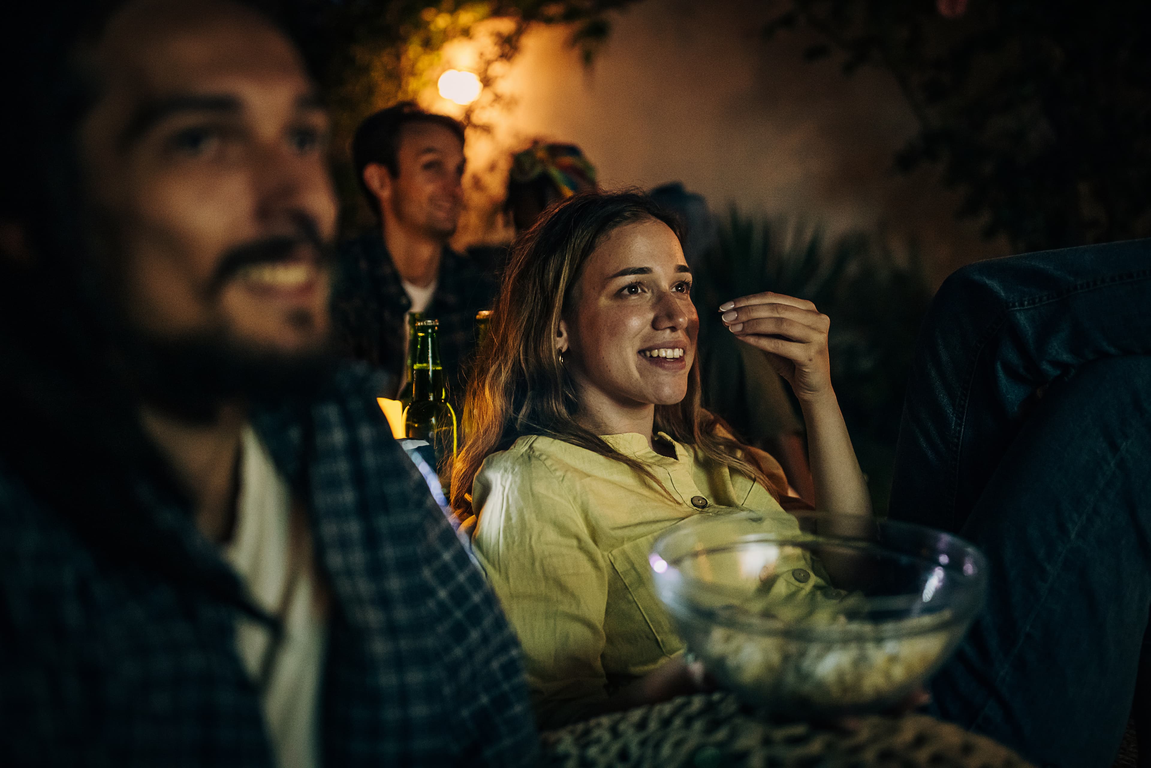 Ein junger Mann und eine junge Frau schauen einen Film im Freiluftkino und essen Popcorn.