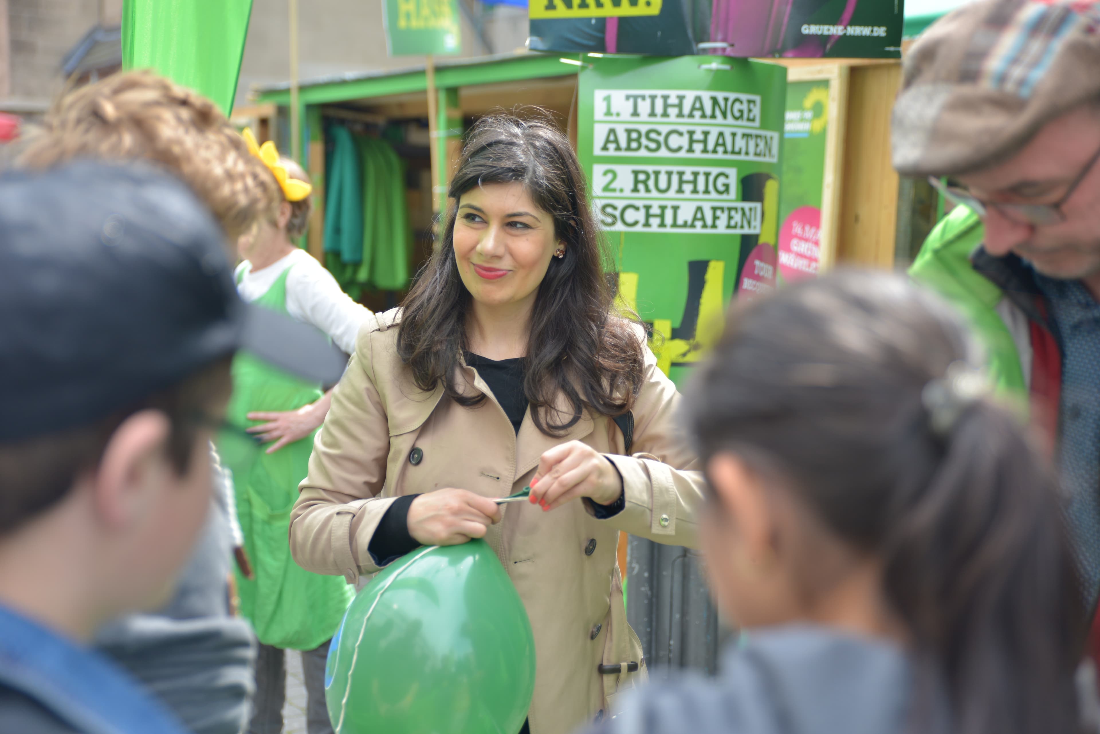 Im Bildmittelpunkt steht eine Frau, die einen Luftballon zusammenknotet. Es stehen Personen um sie herum, die die Straßenaktion betrachten.