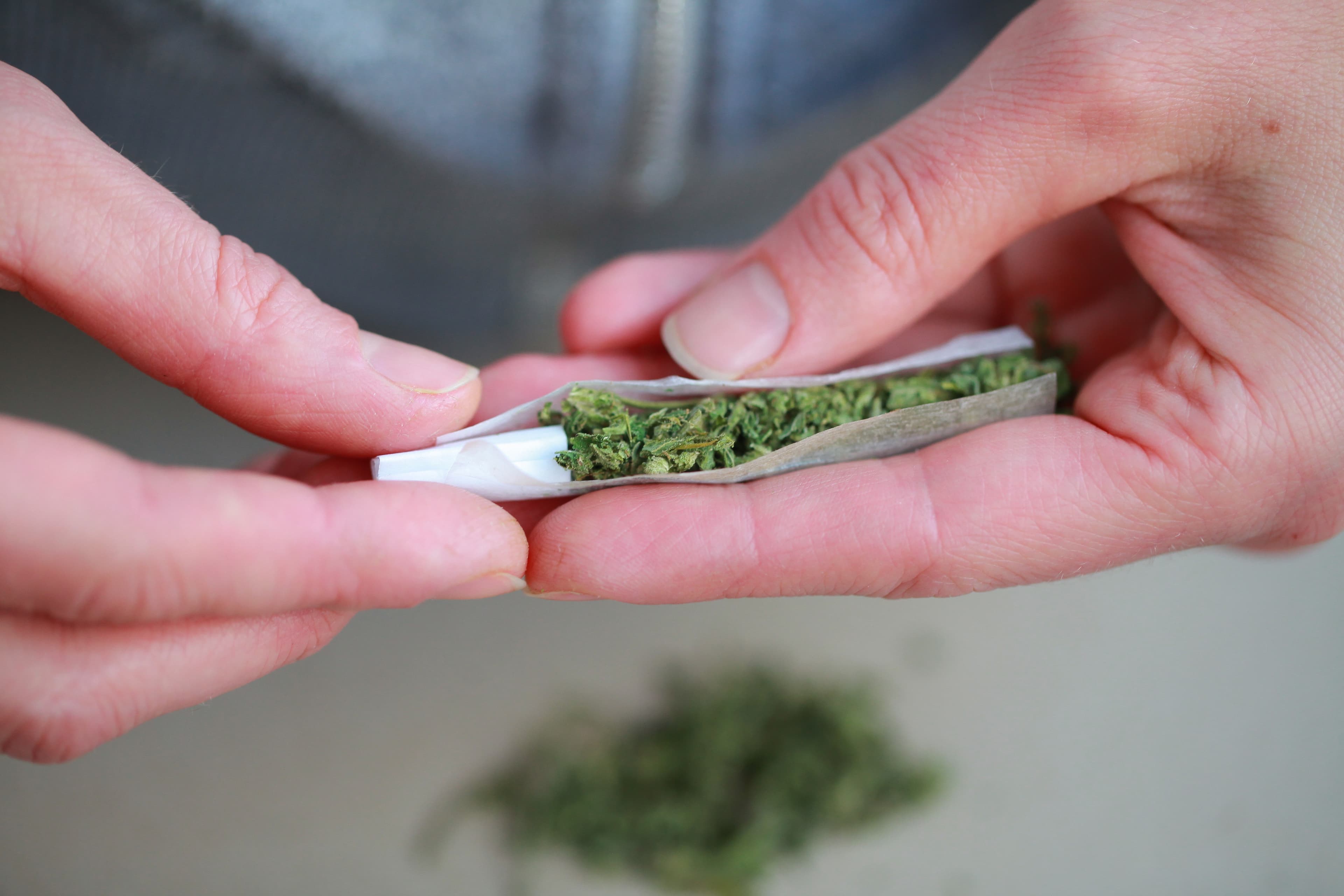 Nahaufnahme von zwei Händen, die einenm Joint drehen.