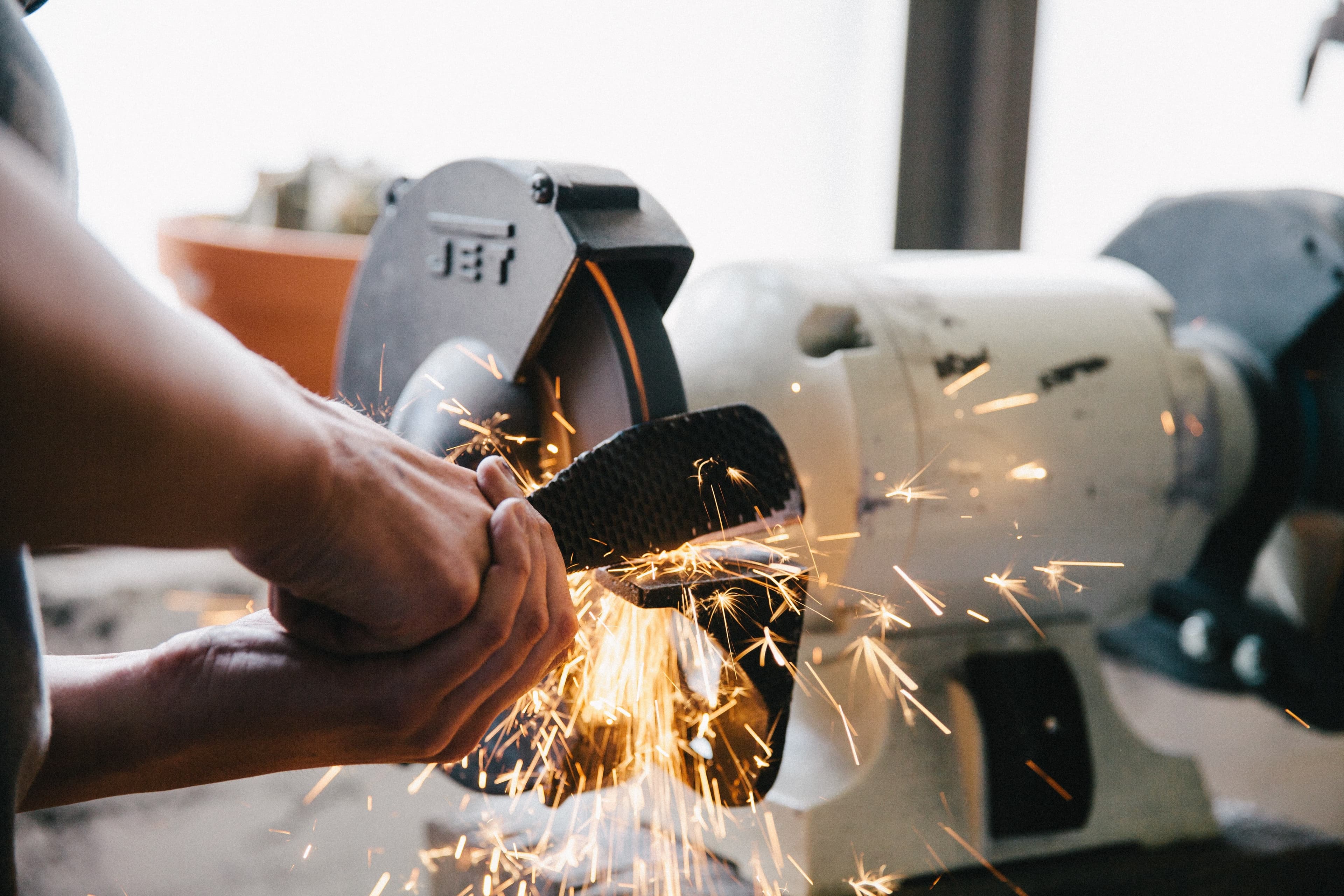 EIn Handwerker schleift eine große Metallpfeile, dabei fliegen Funken.