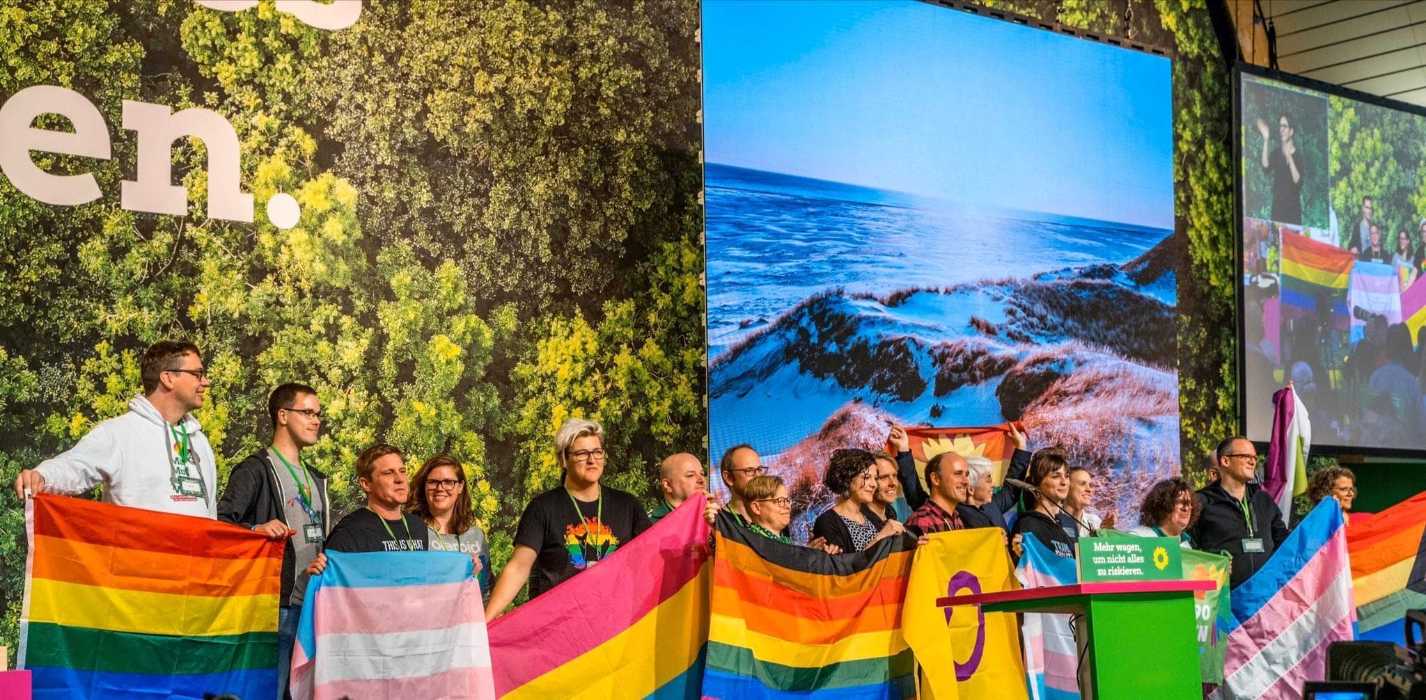 Viele Menschen mit Regenbogenfahnen auf der grünen Parteitagsbühne im November 2019 in Bielefeld.