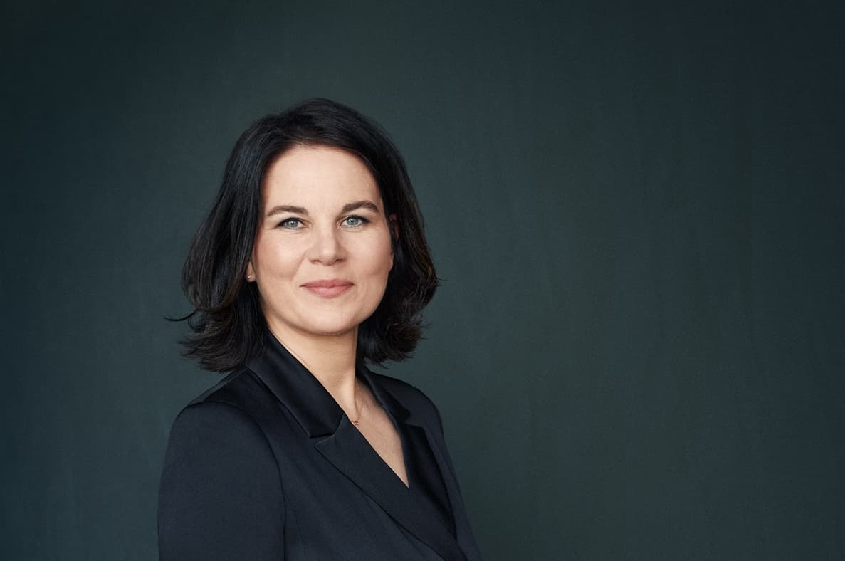 Portrait von Annalena Baerbock in einem schwarzen Kleid vor einem dunklen Hintergrund