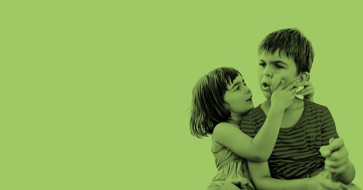 Zwei Kinder, das eine hält das Gesicht des anderen