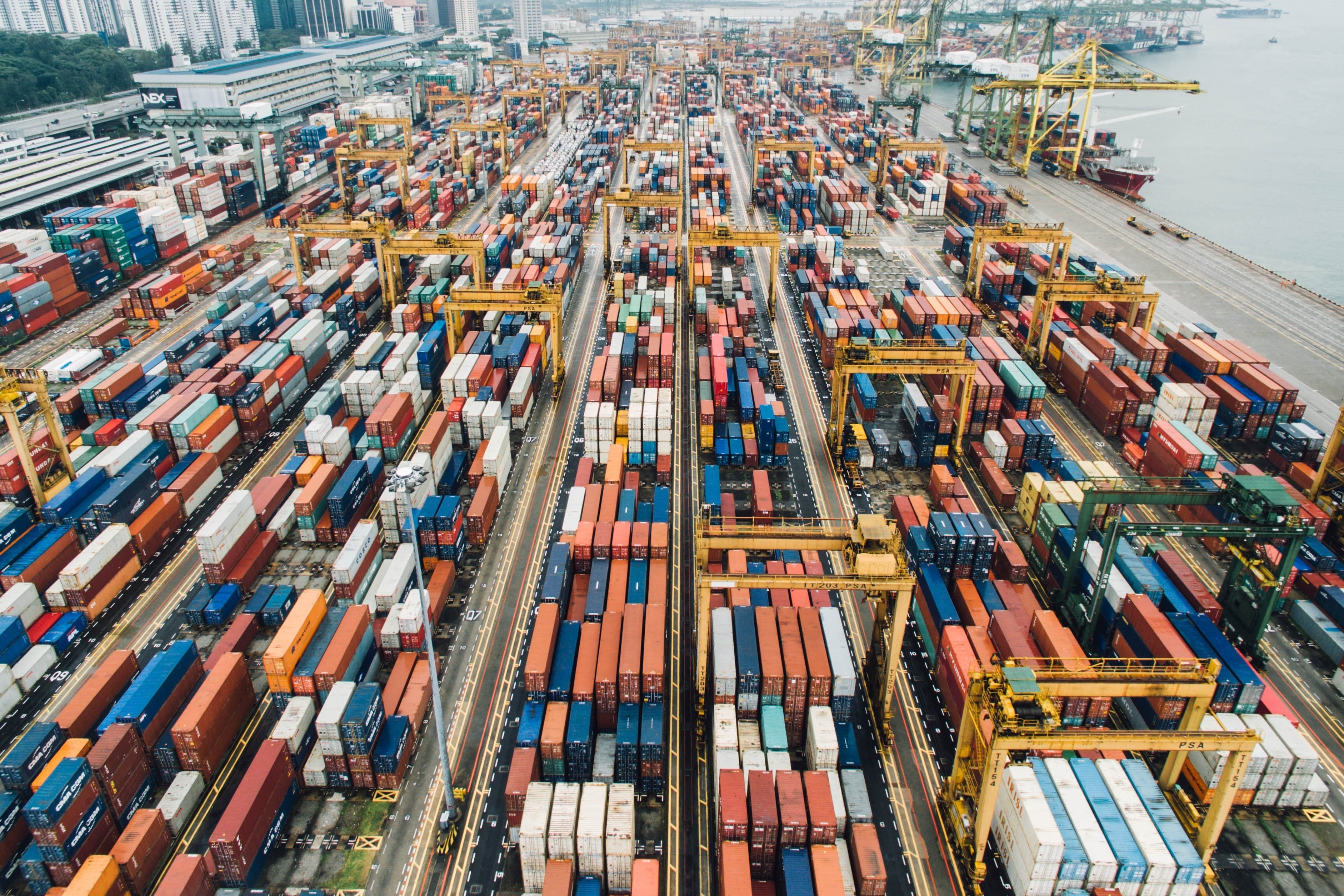Containerabfertigungsbereich im Hafen, mit zahlreichen Containern und Kränen.