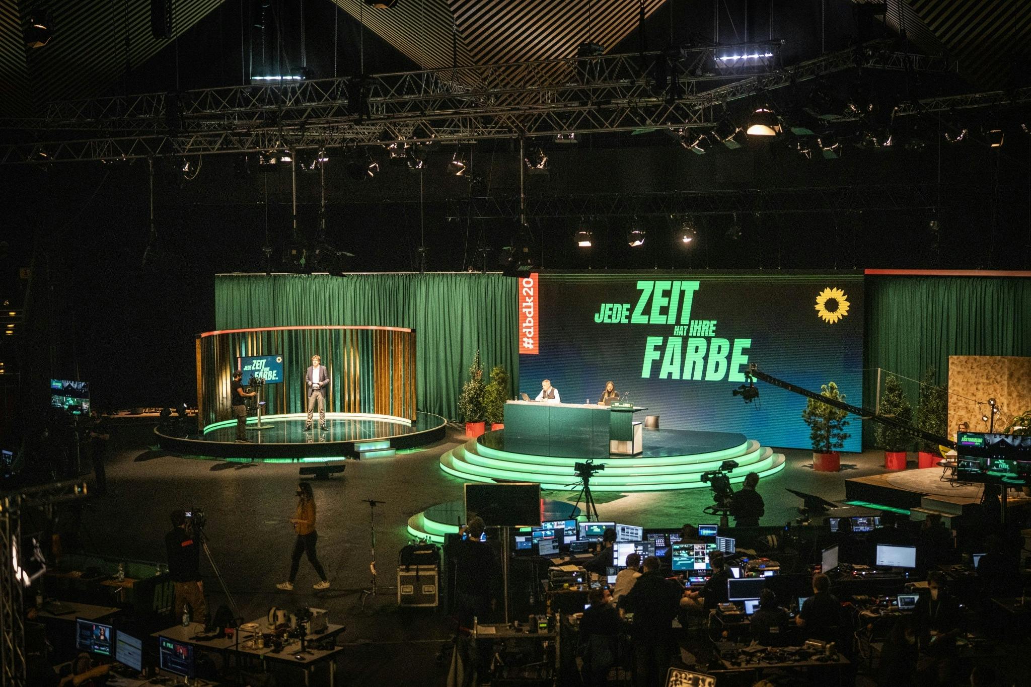 Der Innenraum des Berliner Tempodroms mit einer Bühne mit mehreren Bühnen mit grüner Beleuchtung, im Hintergrund der Schriftzug in Grün: Jede Zeit hat ihre Farbe