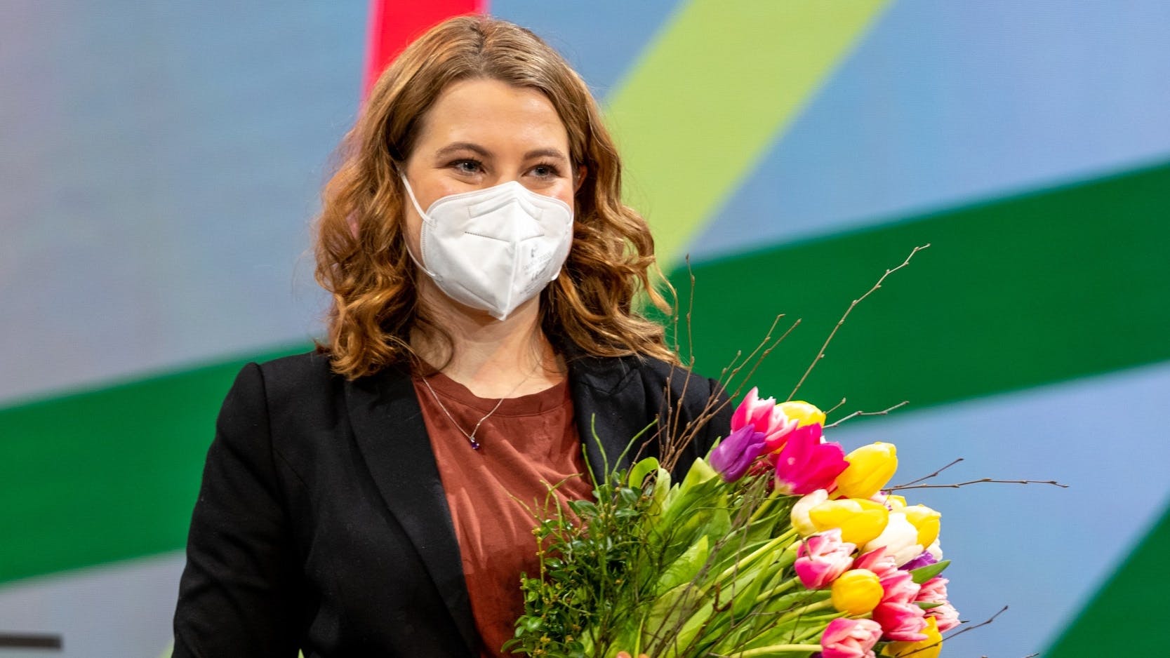 Jamila Schäfer mit Mund-Nase-Schutz und Blumenstrauß im Arm