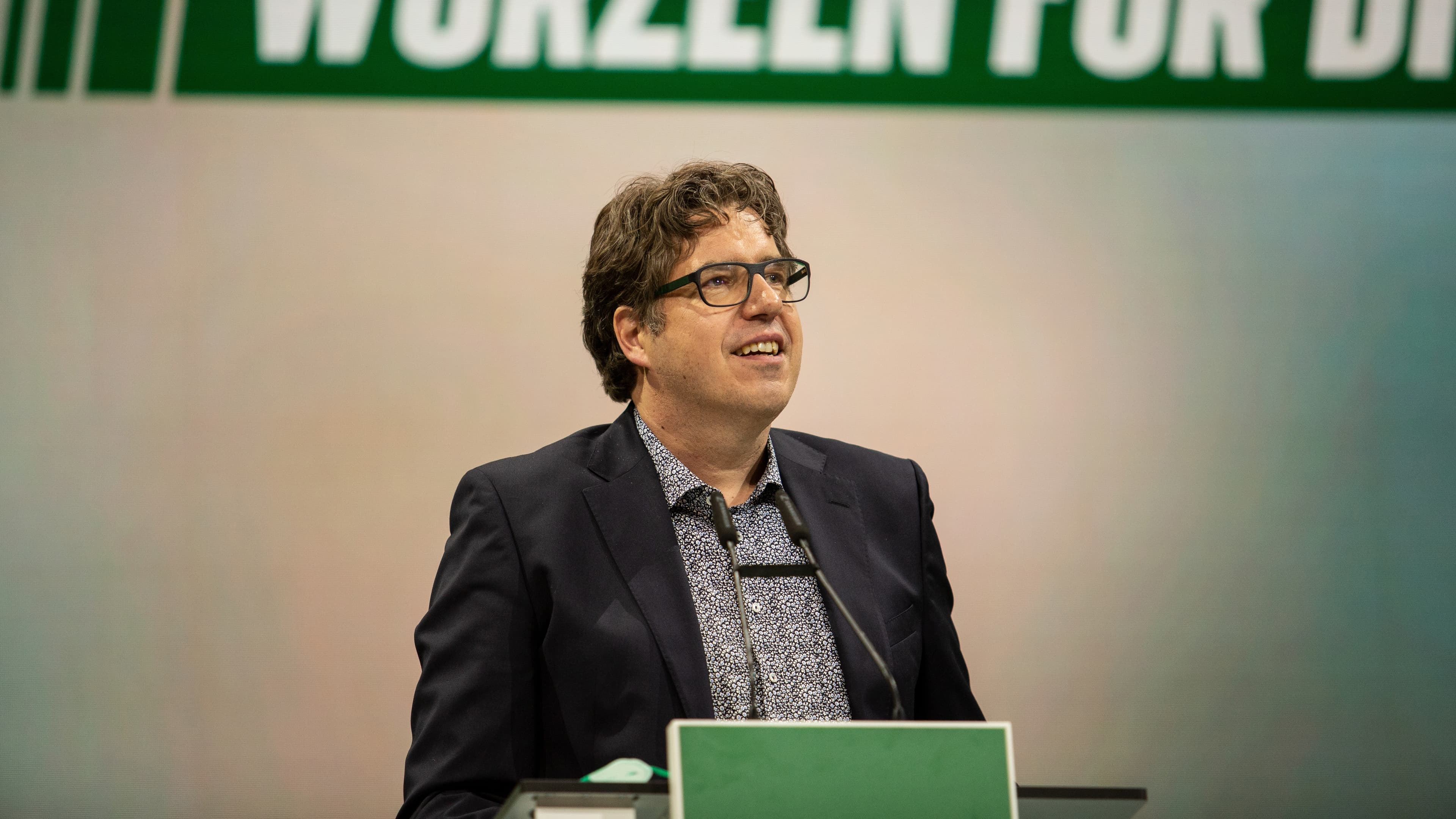 Portrait Michael Kellner hinter einem Redner*innenpult