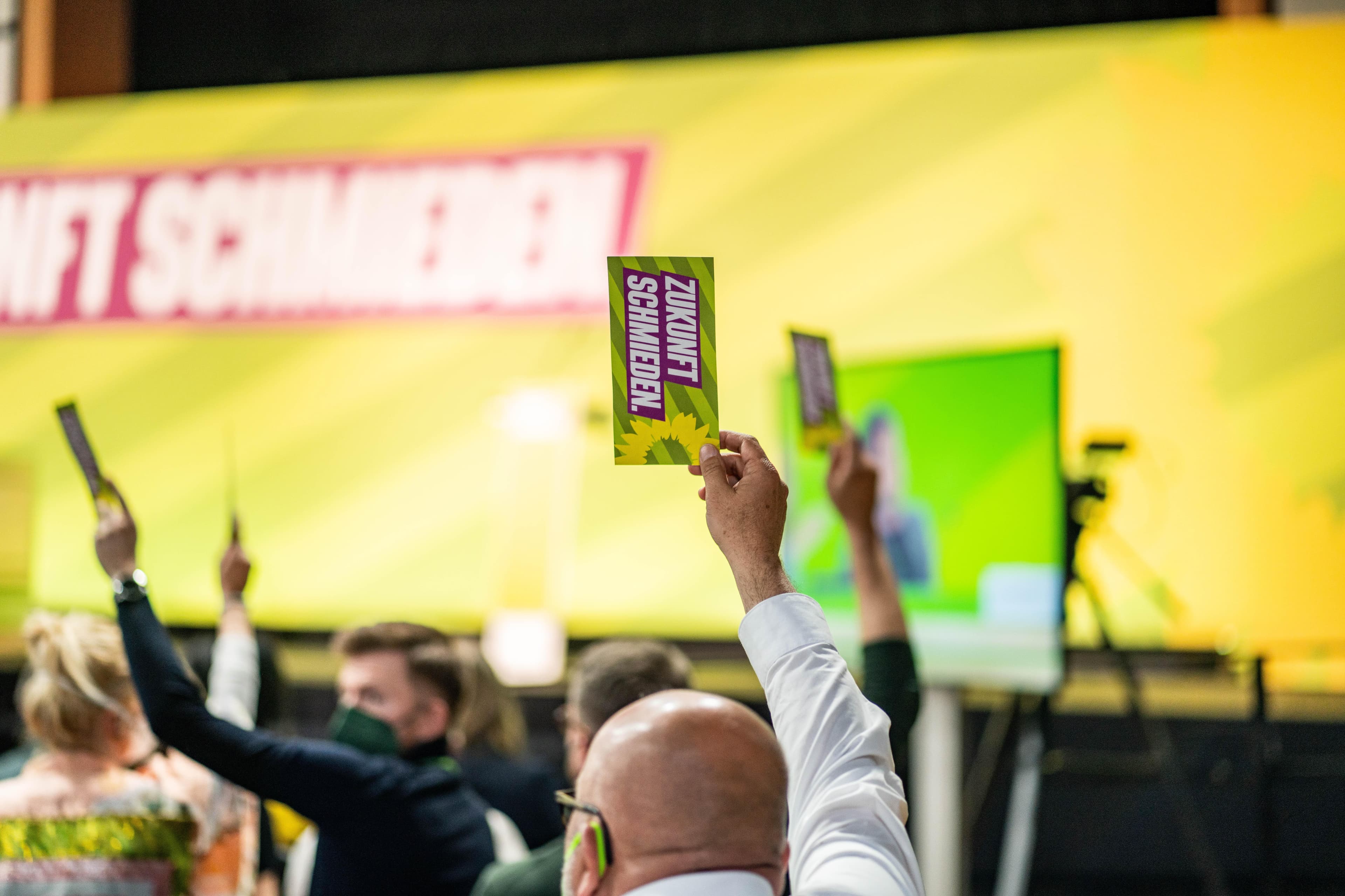 Mehrere Arme heben Stimmkarten in die Luft mit der Aufschrift: "Zukunft schmieden"