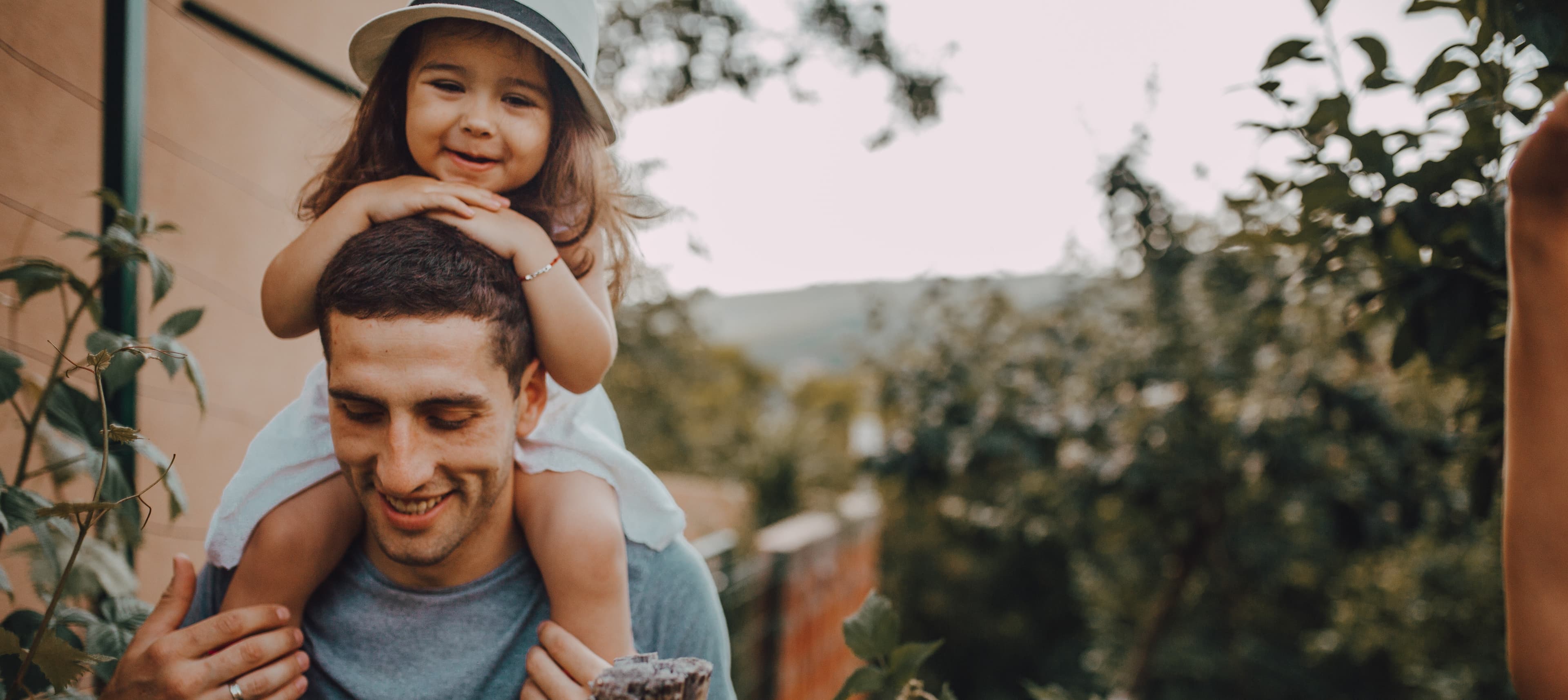 Mann mit Kind auf den Schultern im Garten