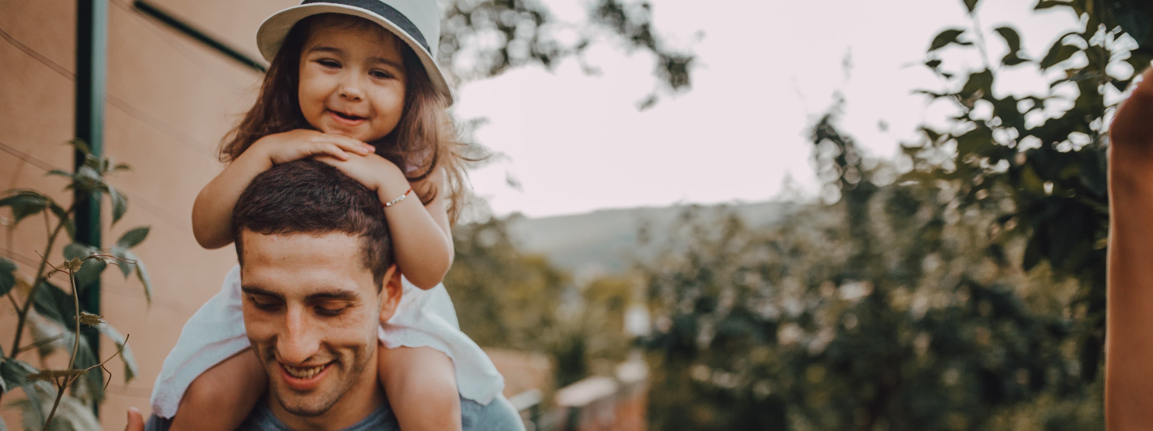 Man mit Kind auf den Schultern im Garten