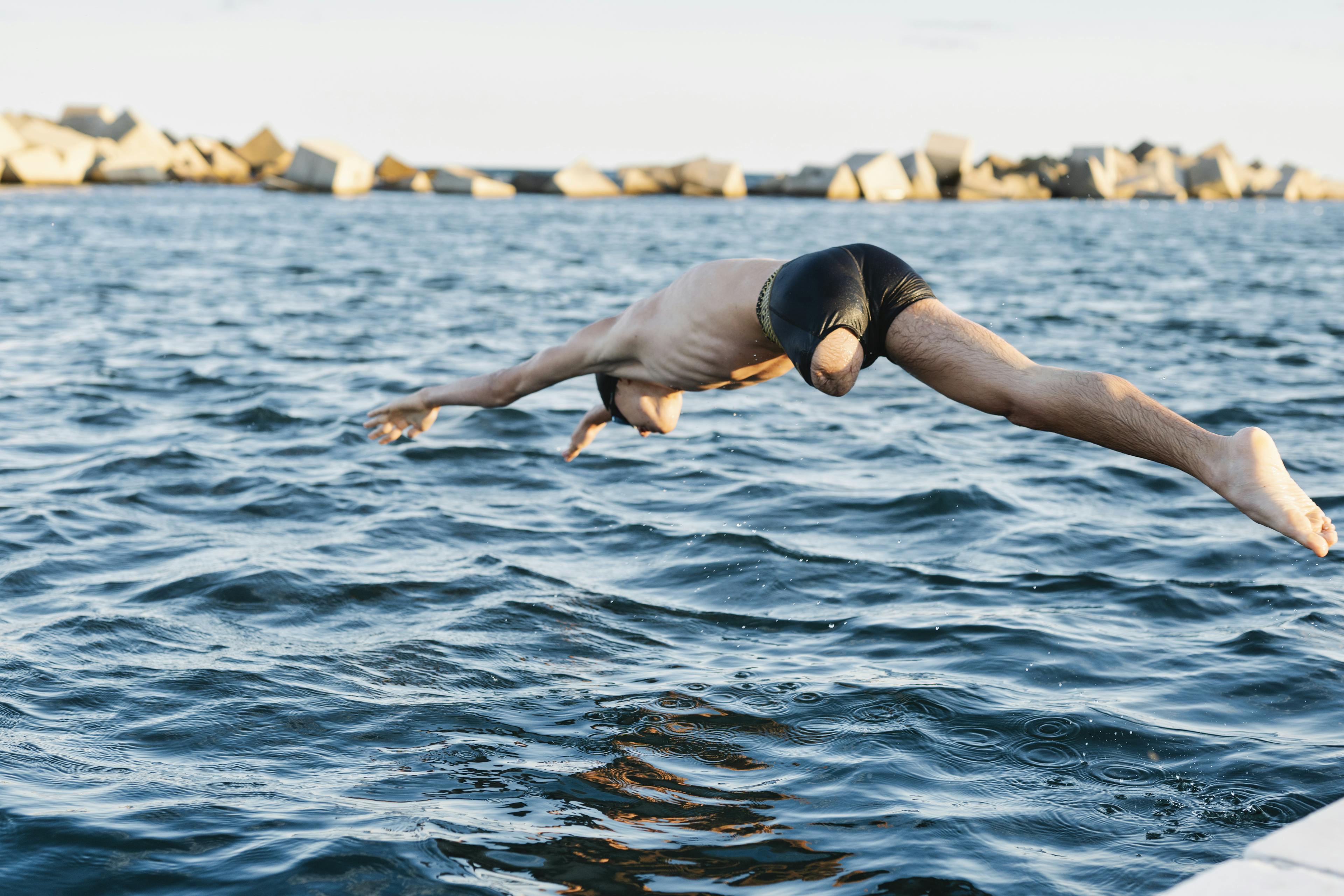 Ein Schwimmer mit einem amputierten Bein macht einen Kopfsprung in den See.