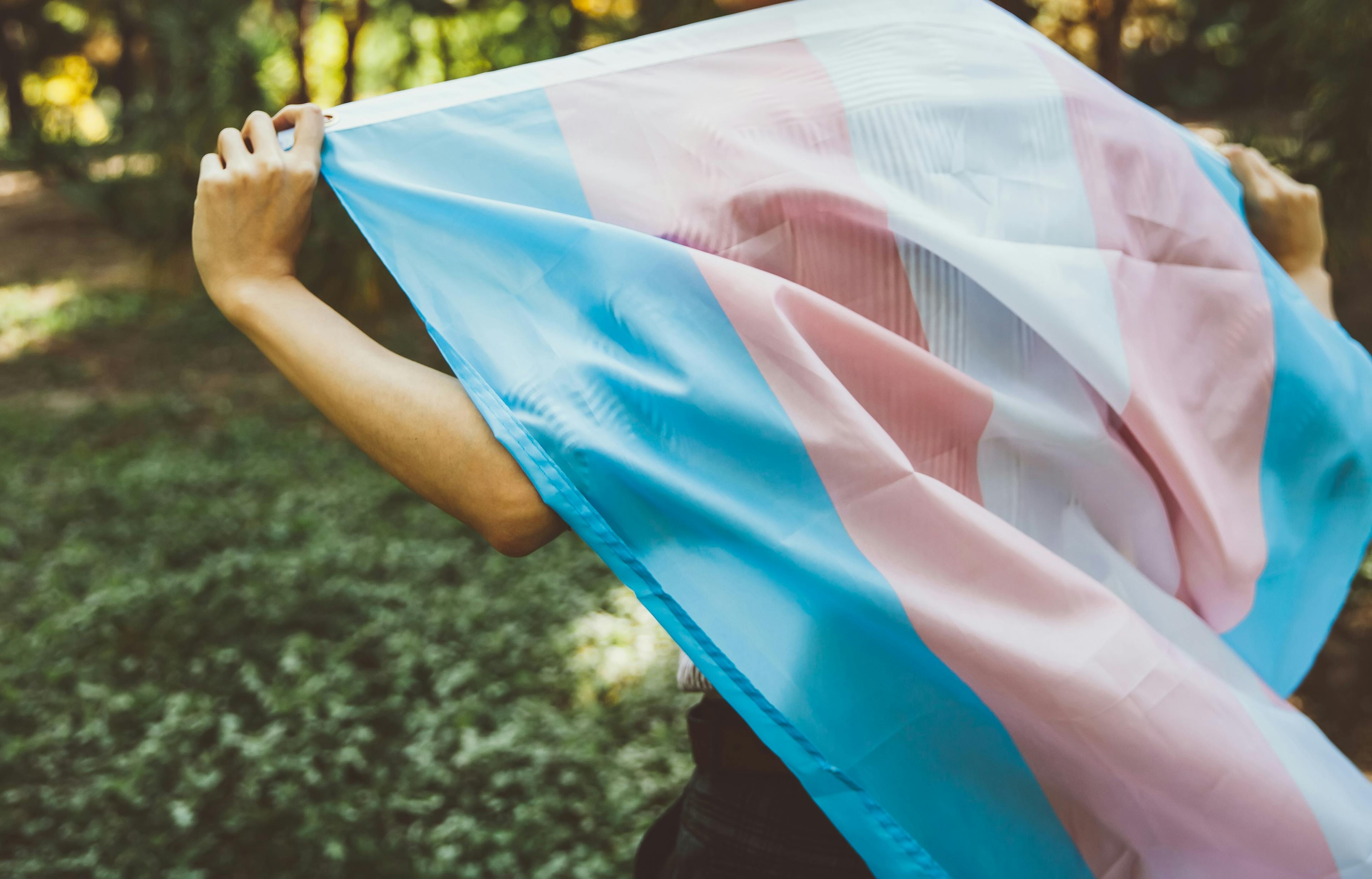Eine Person läuft mit einer wehenden Transgender-Pride Flagge