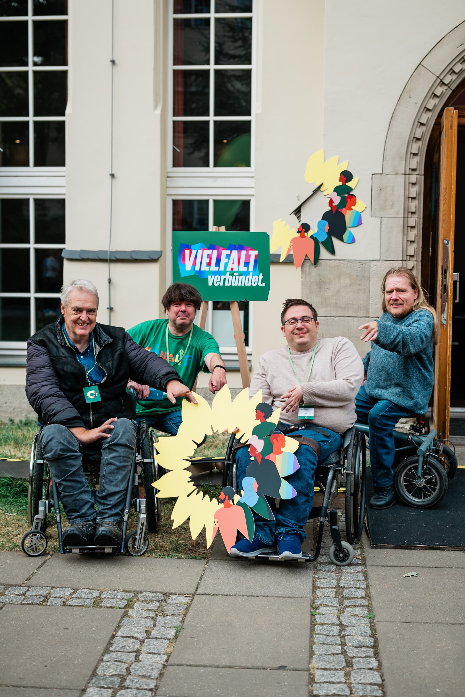 Eine Gruppe Menschen im Rollstuhl posiert mit Plakaten für ein Foto.