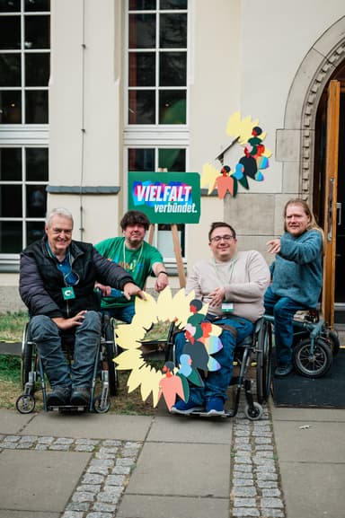 Eine Gruppe Menschen im Rollstuhl posiert mit Plakaten für ein Foto.