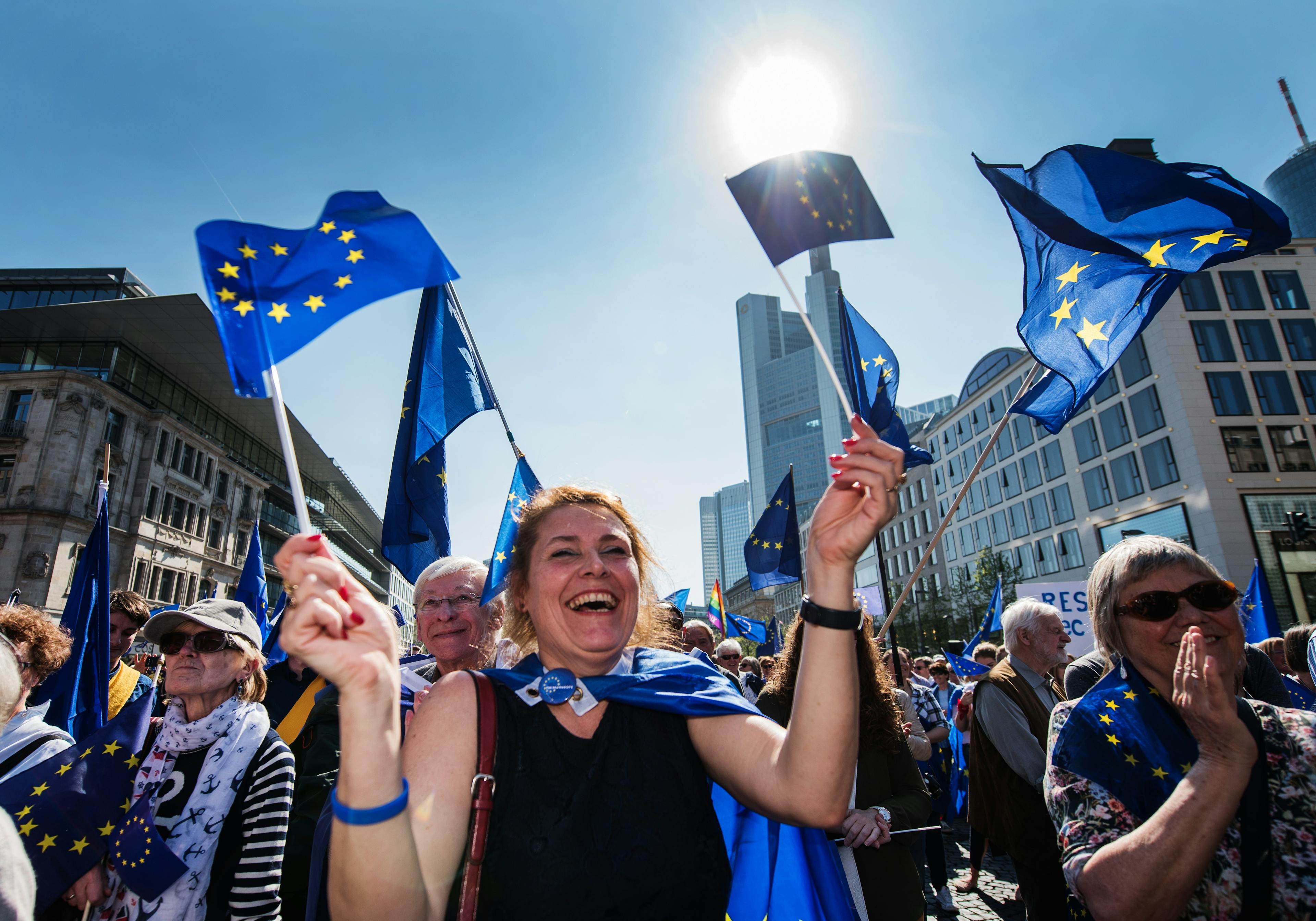 Menschenmenge, die jubeln, applaudieren und Europafahnen in die Luft halten. Im Vordergrund steht eine Frau im Fokus.