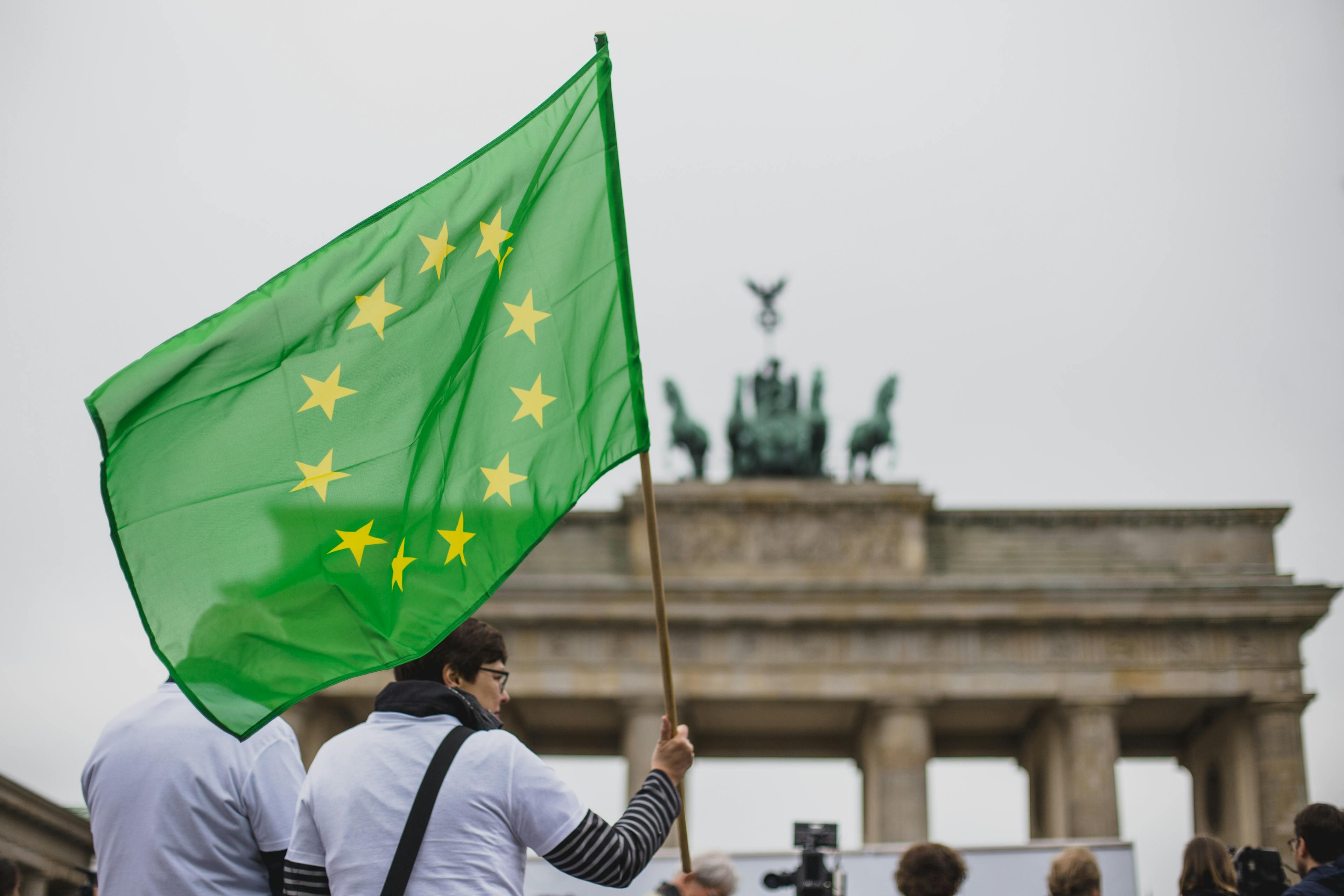 Zwei Menschen mit einer grünen Europafahne sind vor dem Brandenburger Tor zu sehen.