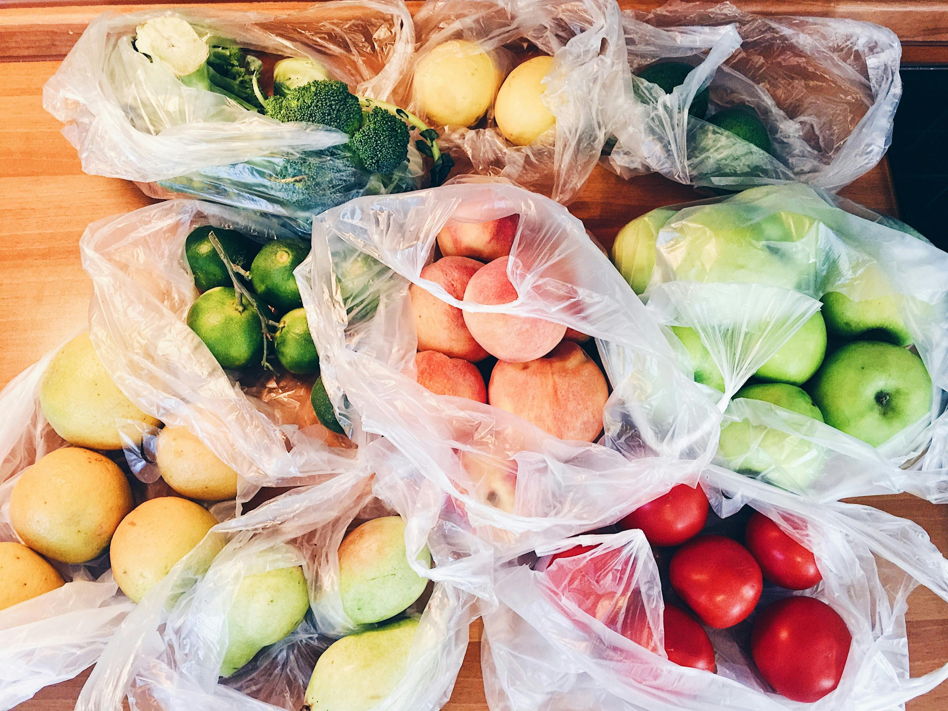 Obst und Gemüse in Plastiktüten verpackt auf einem Tisch.