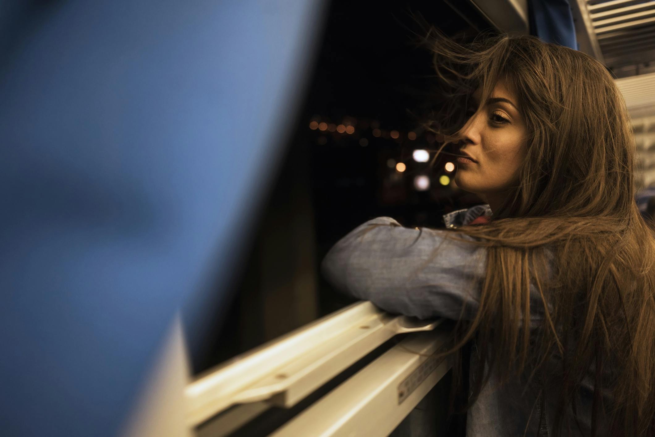 Eine Frau guckt nachts aus dem offenen Zugfenster.