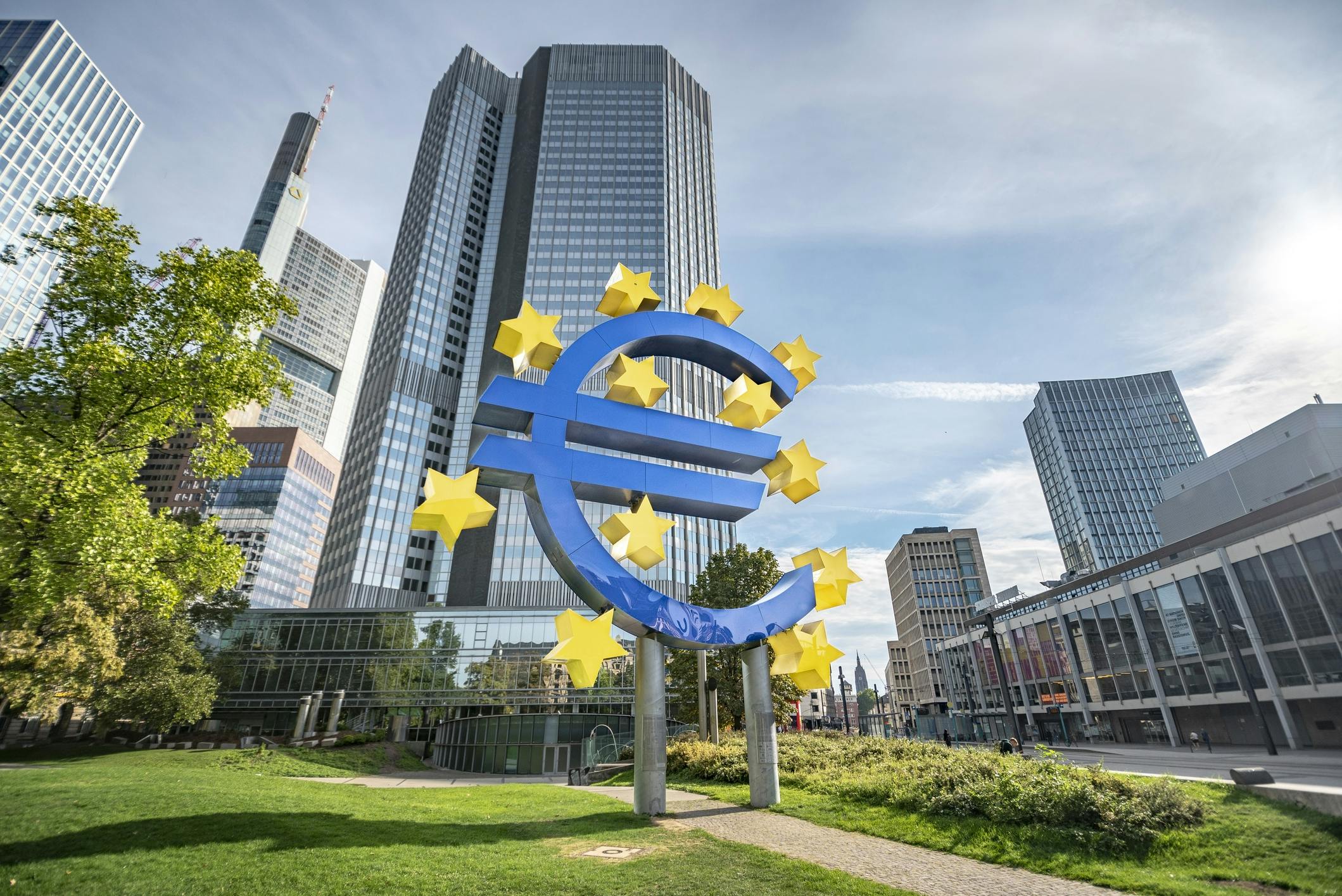 Blick auf das Gebäude der Europäischen Zentralbank mit einem großen Eurozeichen und Europasternen davor.