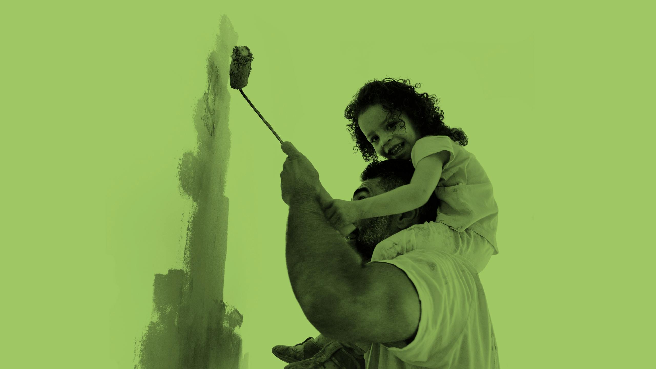 Graustufen auf grünem Hintergrund: Kind sitzt auf den Shcultern eines Mannes und sie streichen gemeinsam eine Wand.
