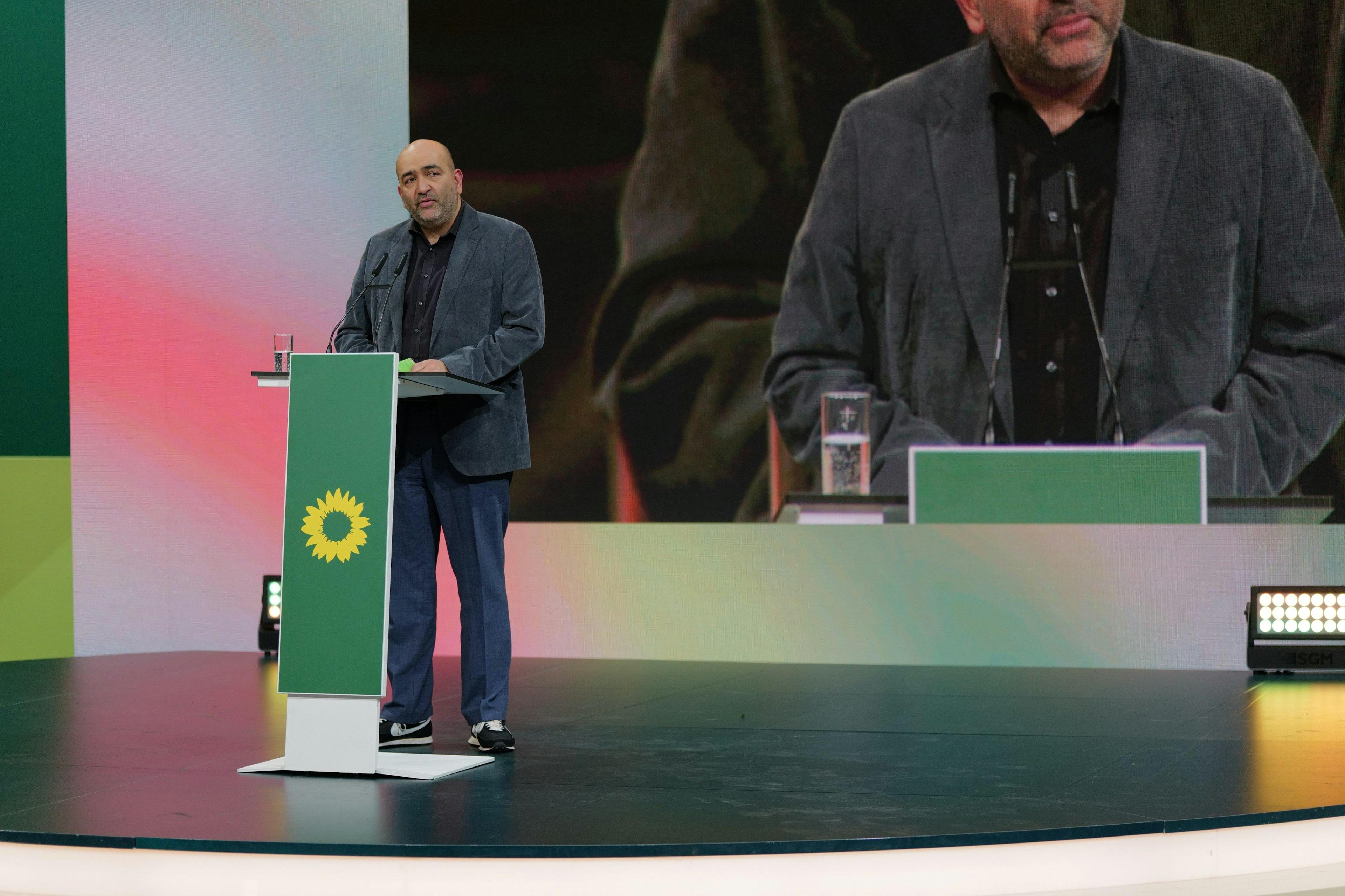 Omid Nouripour steht auf einer Bühne hinter einem Redner*innenpult.