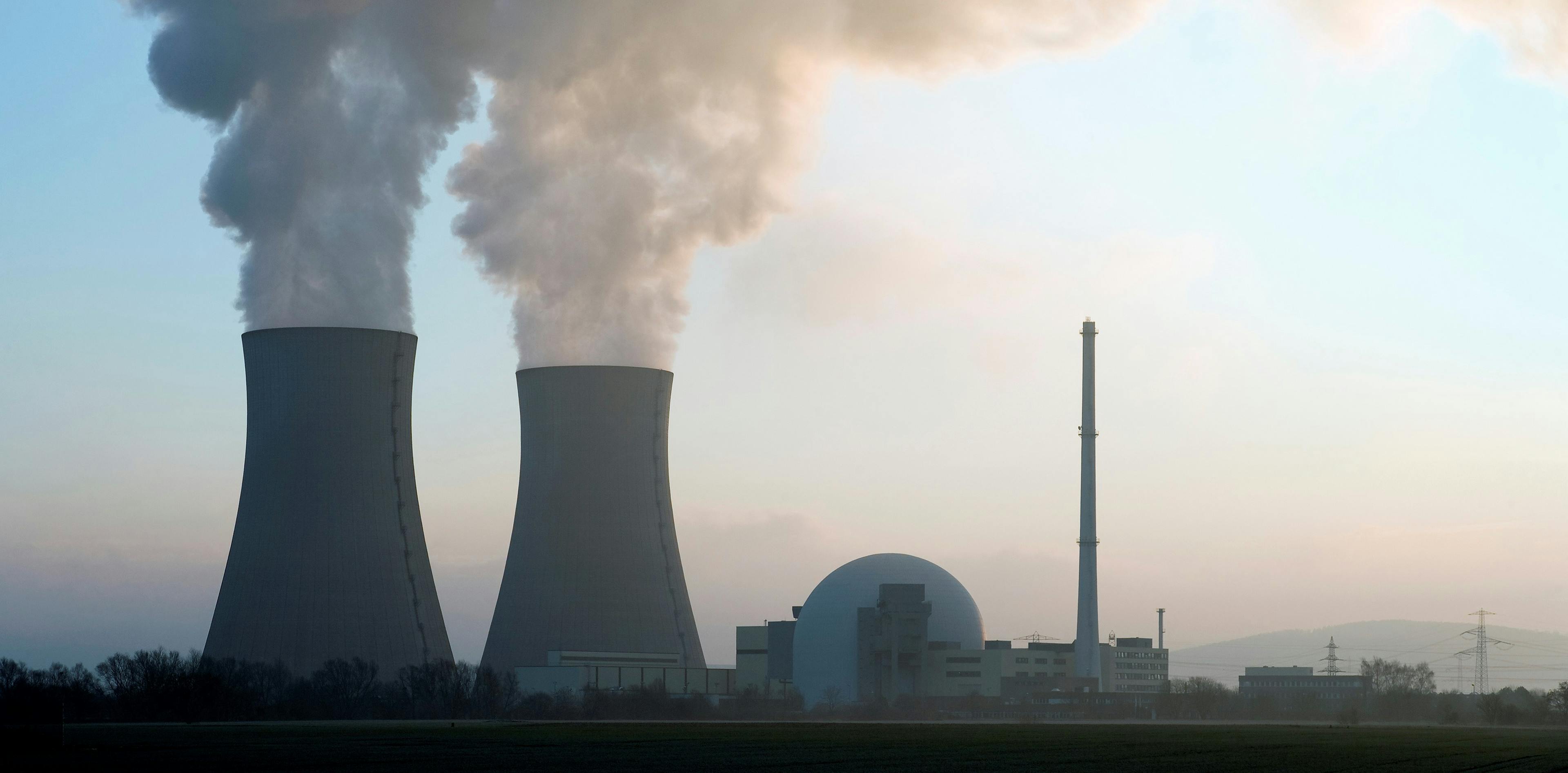 Atomkraftwerk von Weitem mit zwei Kühltürmen, aus denen Dampf kommt