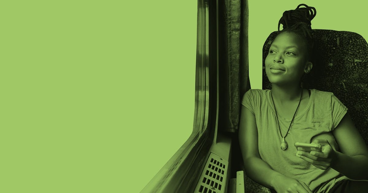 Eine junge Frau sitzt im Zug und sieht aus dem Fenster